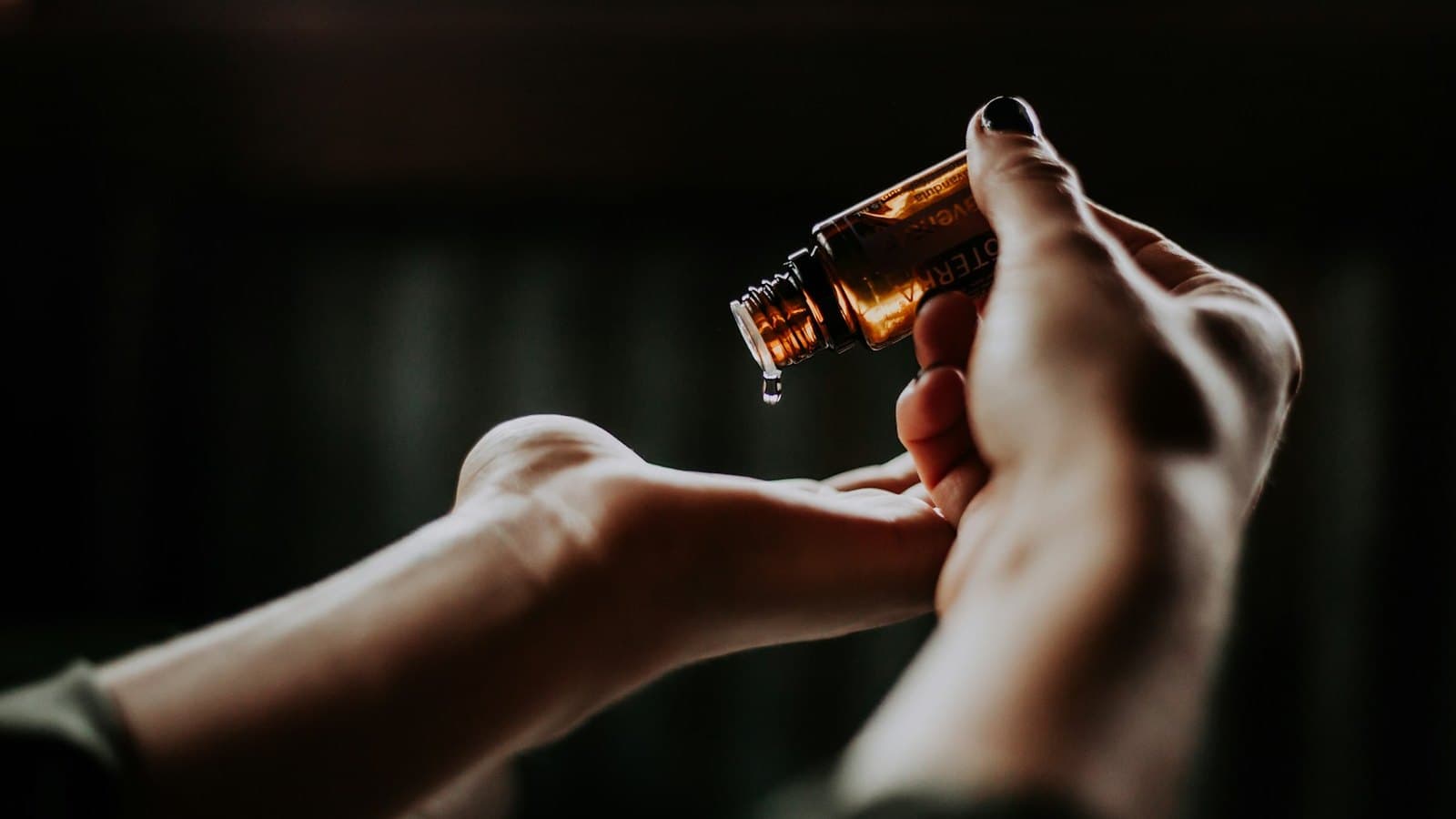 Oil poured from an amber bottle into a therapist's cupped hand