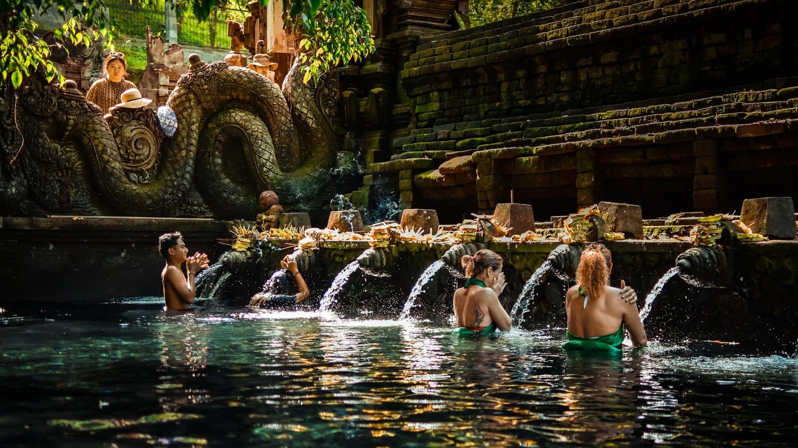Bathers in sarongs and green sashes queueing at the spring-fed purification spouts of Tirta Empul