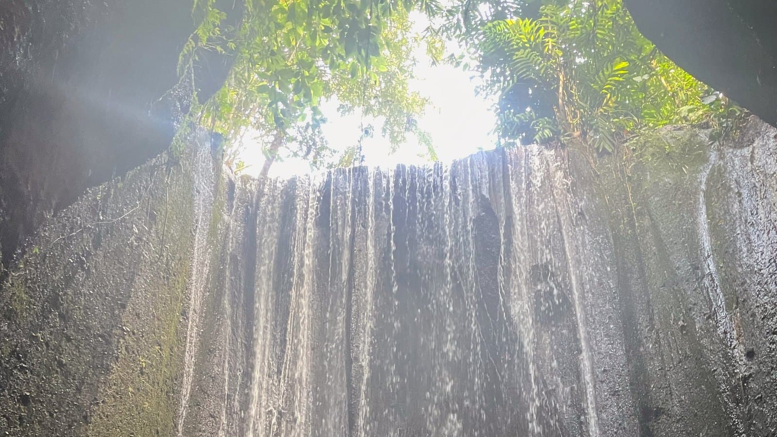 The Tukad Cepung gorge from below, daylight coming through the open cave roof onto the falling water