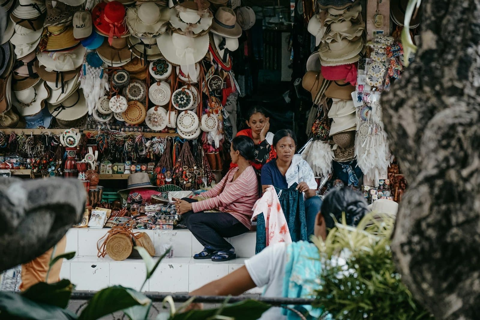 Stallholders among hats and woven crafts at a covered market