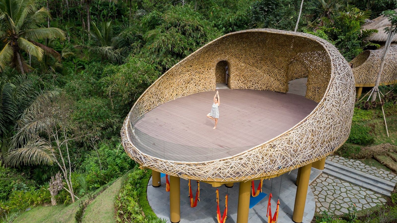 An open-sided practice pavilion built above the tree line, a single figure on the floor inside it