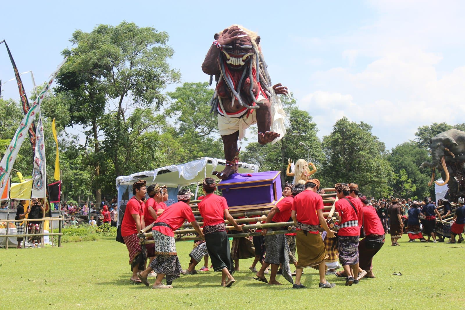 An ogoh-ogoh effigy carried on bamboo poles by a village crowd during the Ngrupuk parade the evening before Nyepi