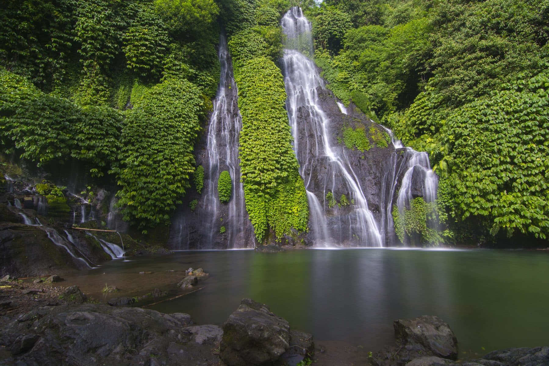 The Banyumala waterfall near Munduk, several falls dropping through dense vegetation into a pool