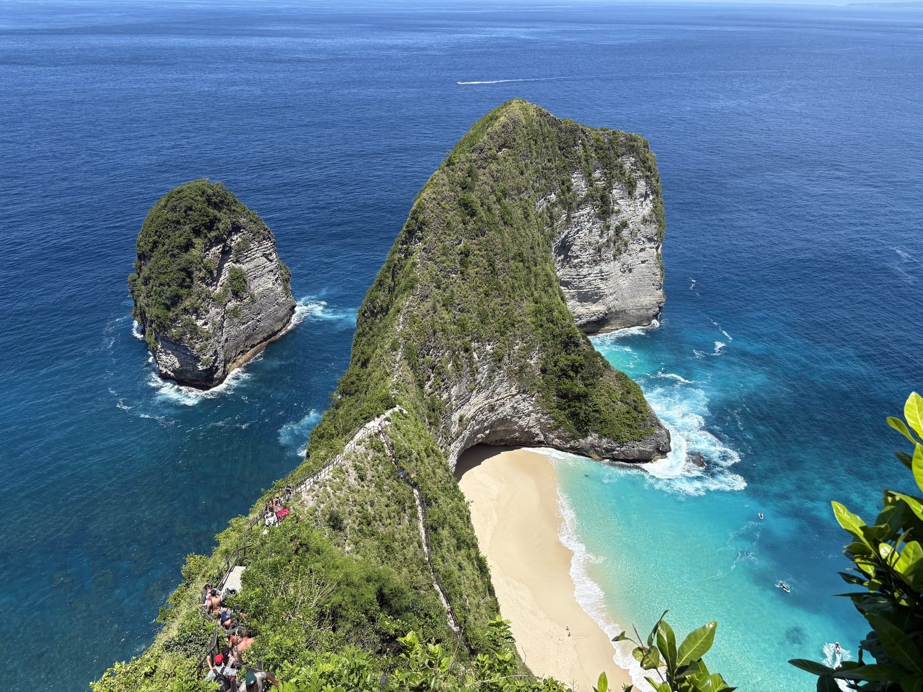 The Kelingking headland on Nusa Penida seen from the clifftop, a green ridge above a white beach and turquoise sea