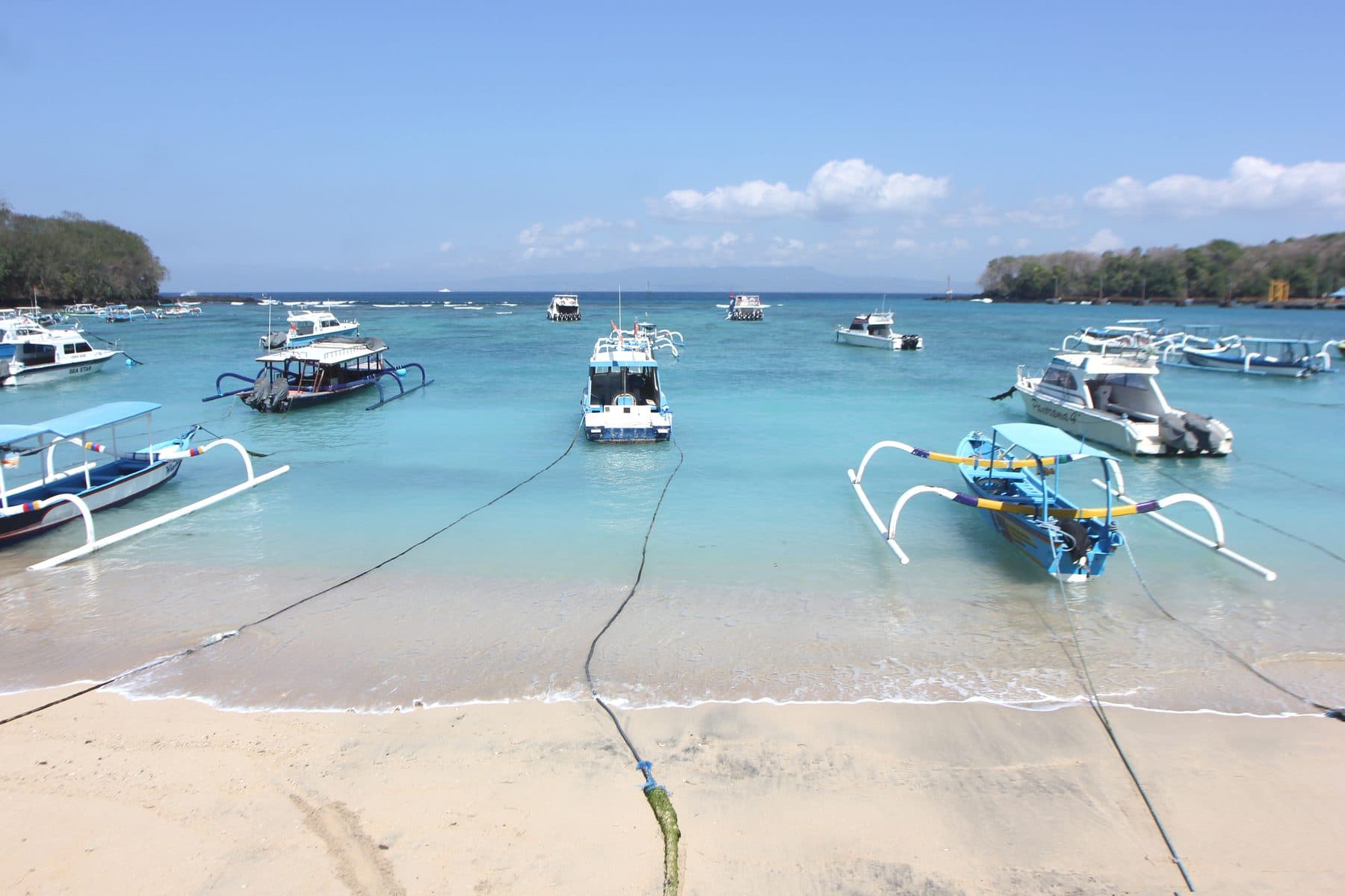 Outrigger boats and small craft moored in the shallow turquoise water off the beach at Padangbai