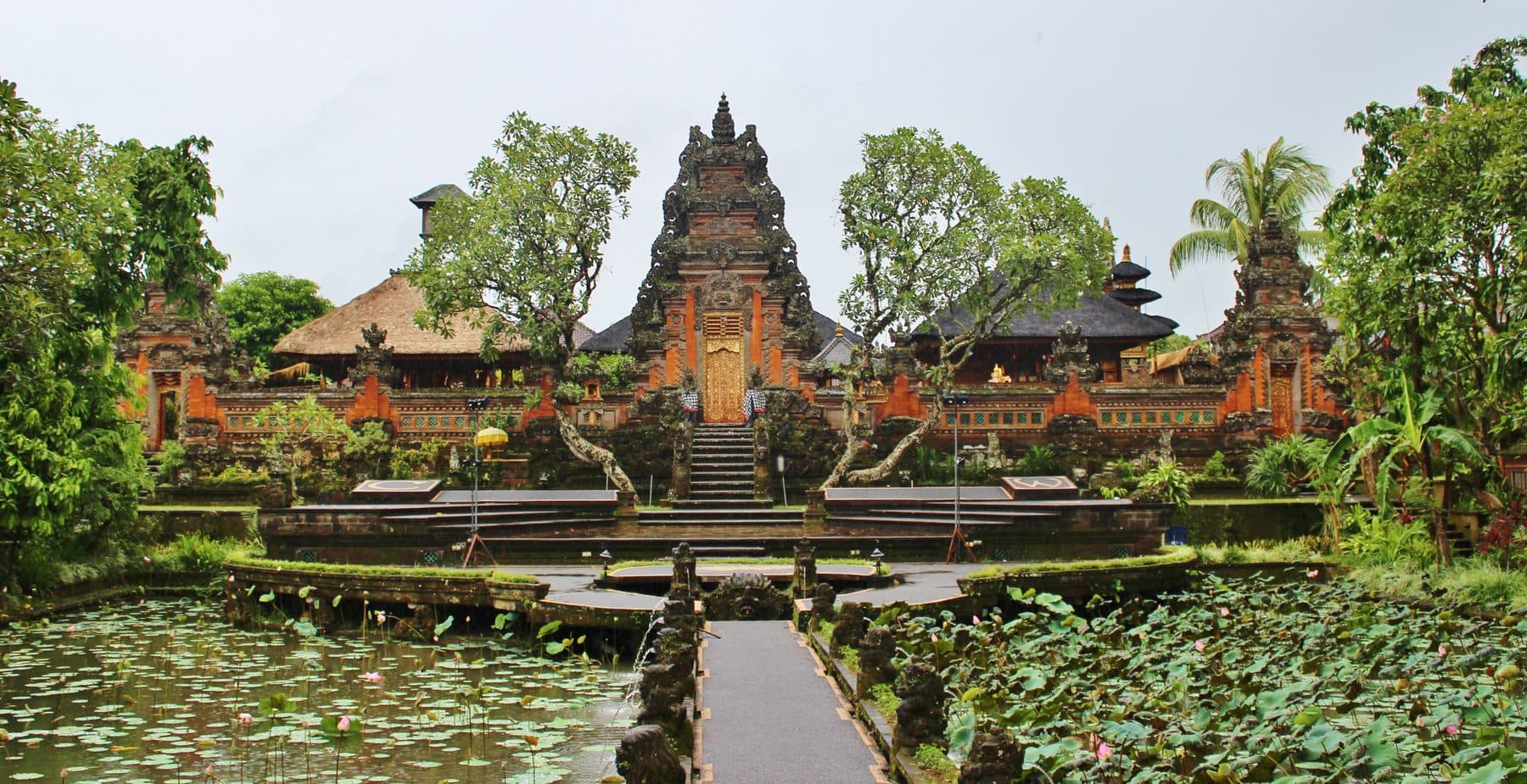 The Saraswati temple in Ubud seen across its lotus pond, with the carved gate and tiered shrines behind the water